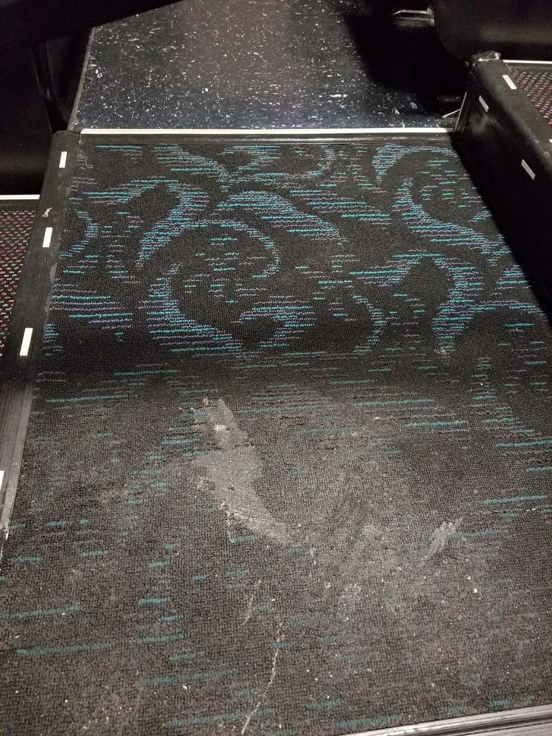 The gallery floor of a plane is covered with a blue carpet.