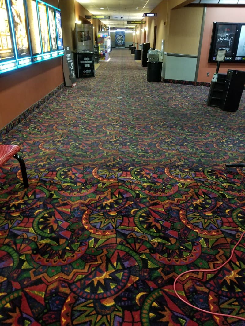 A movie theater with colorful carpets, chairs, and a gallery.