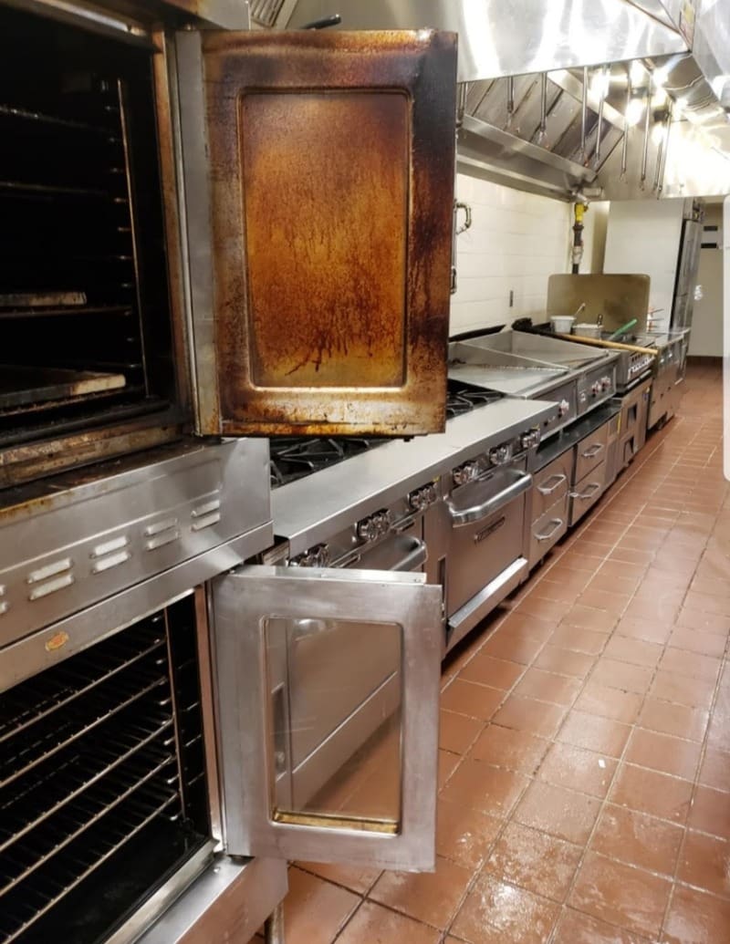 A commercial gallery kitchen with several ovens and oven doors.