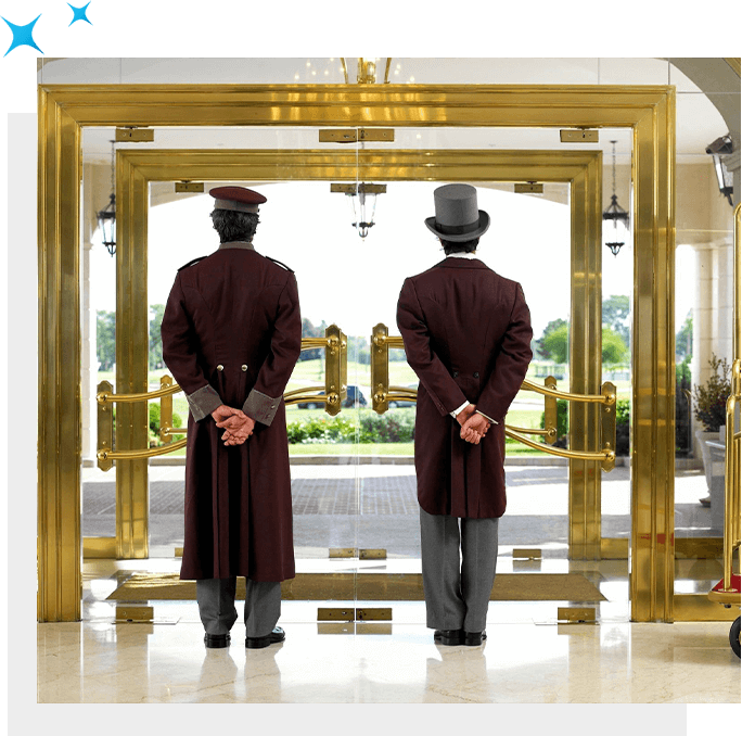 Two men in tuxedos, part of the staffing, standing in front of a golden door.