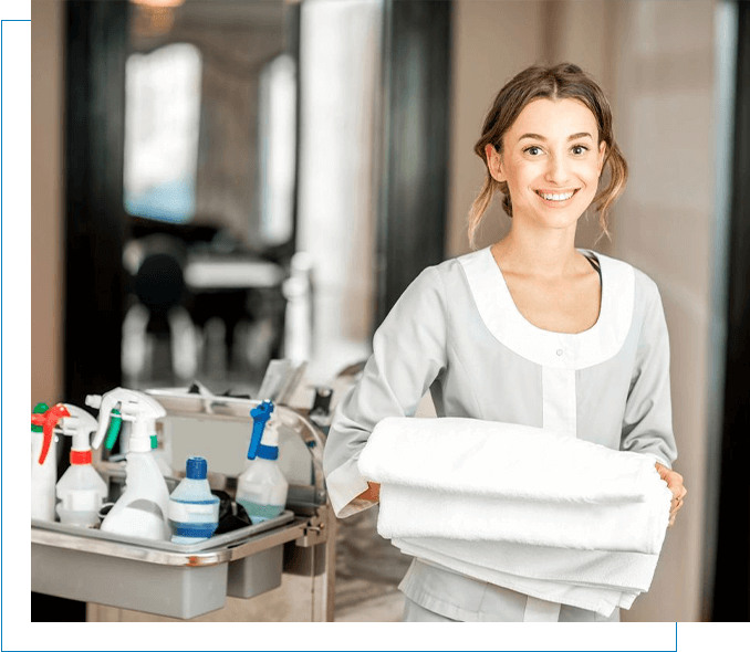 A professional janitorial services worker holding a tray of towels in a hotel.