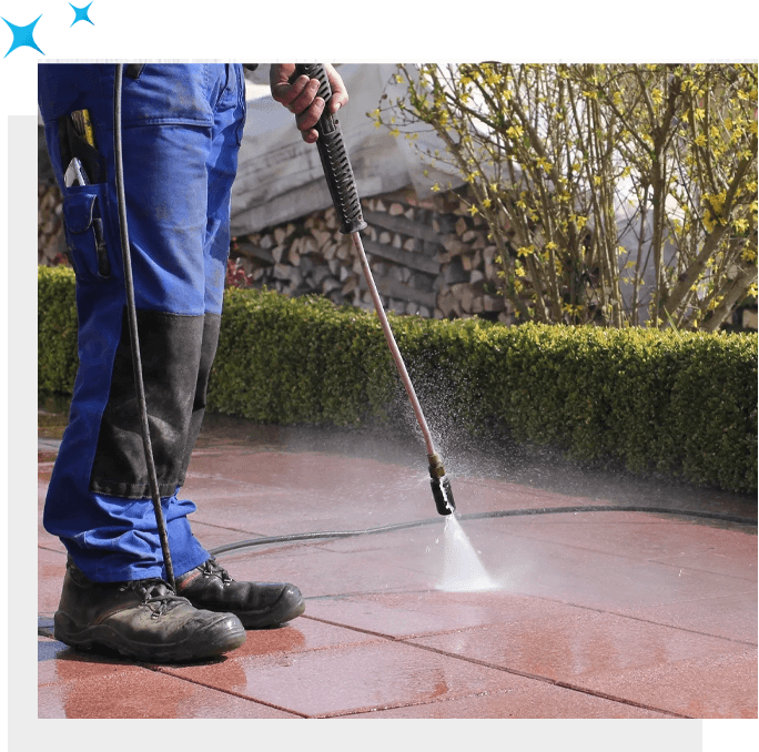 A man using carpet cleaning solutions with a pressure washer to clean a patio.