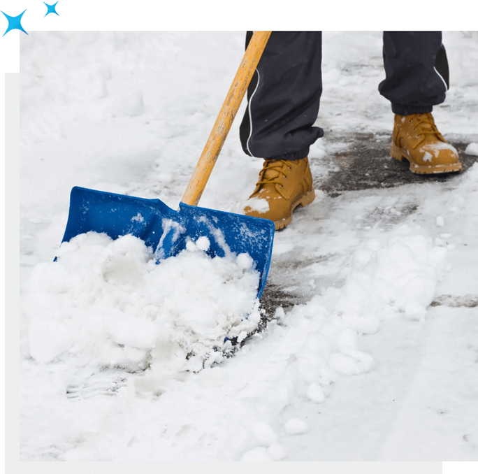 A person shoveling snow with a blue shovel, near an area serviced by Carpet Cleaning Solutions.